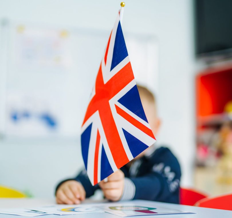 Boy plays with british flag. Child holds the flag of Great Britain. English flag in girl's hands.
